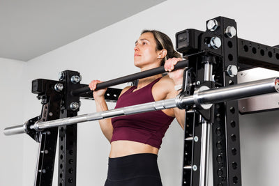 Athlete doing pull-ups behind Smith Machine mounted to the outside of a power rack