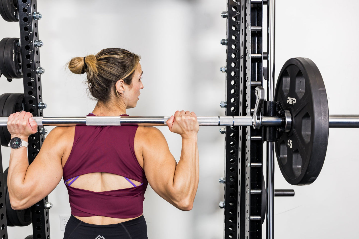 Athlete racking the barbell on the front of a rack mounted Smith Machine