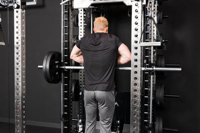 Athlete doing upright rows on the Smith Machine inside a power rack with asymmetrical loading